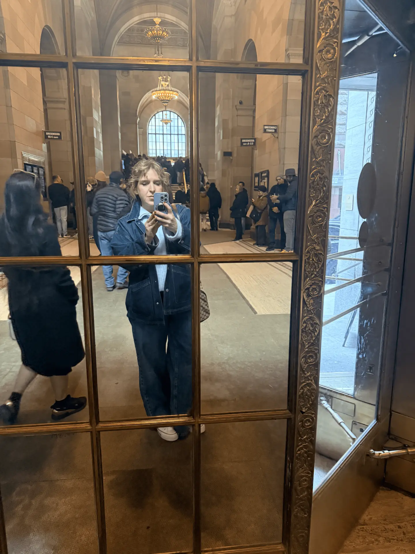 Stacy Silvernail photographed in a mirror inside a grand public library entrance